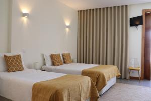 维亚纳堡Enjoy Viana - Guest House的酒店客房,配有两张床和椅子