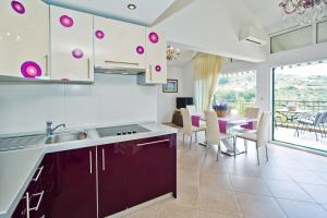 赫瓦尔Island Hvar Seaside Villa Levanda with Beach, Pool & Seaview的一个带紫色橱柜的厨房和一个饭厅