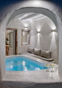 伊亚Marble Sun Villa with Jacuzzi by Caldera Houses的一个带沙发和两杯酒杯的房间的游泳池