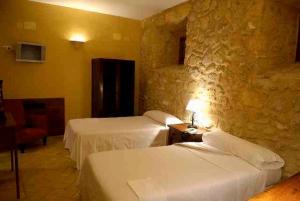 奥苏纳修道院旅馆的酒店客房设有两张床和石墙。