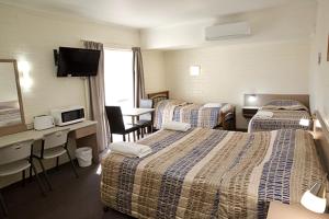贡迪温迪Pioneer Motel Goondiwindi的酒店客房设有三张床和一张书桌
