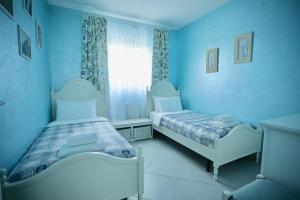 佩兹迪格雷科Dimora di Luce的蓝色的客房设有两张床和窗户。