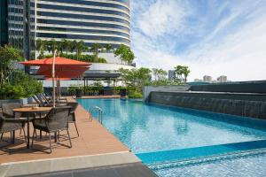 新加坡Holiday Inn Singapore Little India, an IHG Hotel的一个带桌椅和遮阳伞的游泳池