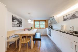 施瓦岑贝格WÄLDERHAUS Apartments的厨房配有白色橱柜和木桌