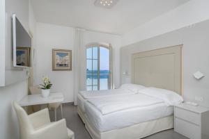 马尔切西内维加酒店的白色卧室配有床、书桌和椅子
