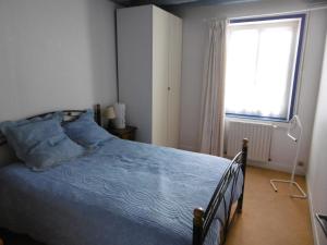 Auzouer-en-TouraineLA MUSARDIERE的一间卧室配有一张带蓝色棉被的床和窗户。