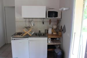瓦劳里埃le petit bois的小厨房配有白色橱柜和水槽