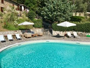 古比奥La Panoramica Gubbio - Maison de Charme - Casette e appartamenti self catering per vacanze meravigliose!的一个带椅子和遮阳伞的大型游泳池