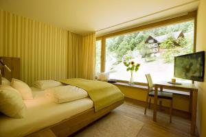 多恩比恩Hotel Alpenrose Ebnit的一间卧室配有一张床、一张书桌和一个窗户。