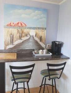 卡文迪西Simply Charming Cottages的一张带遮阳伞和两把椅子的木板路画