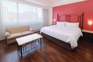 瓜达拉哈拉历史中心假日套房酒店的酒店客房设有一张大床和一张沙发。
