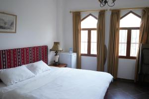 尼兹瓦Date Palm Inn的卧室配有白色的床和2扇窗户。