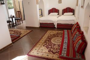 尼兹瓦Date Palm Inn的两张床铺,位于一间有两块地毯的房间