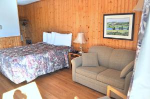 卡文迪西维斯塔湾酒店的一间卧室配有一张床、一张沙发和一把椅子