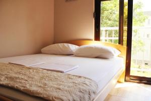 代诺维奇Mimoza Apartments的一张带白色床单和枕头的床,靠窗