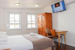 悉尼Glasgow Arms Hotel Ultimo的一间卧室配有一张床、一张书桌和一台电视。