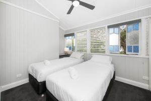 汤斯维尔美丽的昆士兰度假屋的配有2张床的白色墙壁和窗户客房