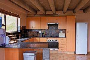 马加利斯堡Mahikeng Lodge的厨房配有木制橱柜和白色冰箱。