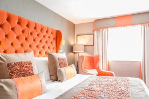 赫斯沃尔Thornton Hall Hotel & Spa的一间卧室配有一张带橙色床头板的大床