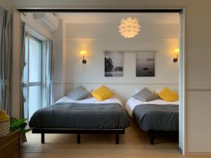 冲绳岛市Allstay CHIBANA的配有镜子的客房内的两张床