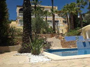 圣埃乌拉利亚Casa Grecia的棕榈树和游泳池的房子