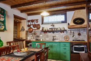 多尔加利La casa del Balivo的厨房配有绿色橱柜和一张带一碗水果的桌子
