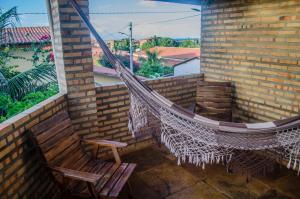 卡诺格布拉达Pousada Morada do Sol的阳台配有吊床、椅子和窗户