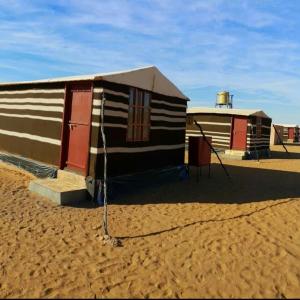 Aflāj巴迪雅沙漠营地酒店的几座小建筑坐在沙子里