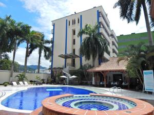 比亚维森西奥Hotel Maria Gloria的棕榈树建筑前的游泳池