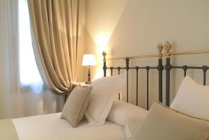 桑坦德乐珀蒂精品酒店的一张带白色枕头的床和一盏靠窗的灯