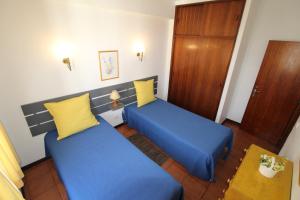 波尔蒂芒ApartamentoSolPraia - BeloHorizonte的两张床铺,配有蓝色和黄色枕头