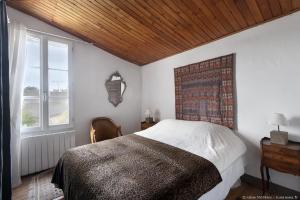 滨海拉库阿尔德Le Clos du Vieux Porche的一间卧室设有一张带木制天花板的大床