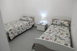 拉古萨Casa Felice的一间卧室配有两张床和一张带台灯的桌子