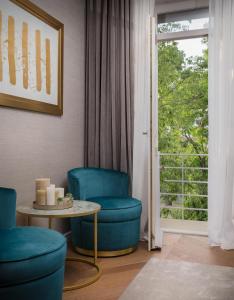 斯普利特Five Elements Luxury Rooms的客厅设有蓝色的椅子、桌子和窗户