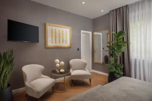 斯普利特Five Elements Luxury Rooms的一间卧室配有两把椅子、一张桌子和一台电视。