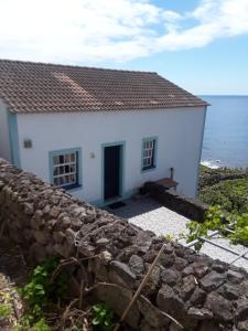 Fajã de São JoãoCasa da Matilde的海边的白色房子,有石墙