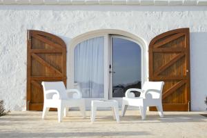 埃斯米洪格兰比尼高斯贝尔乡村酒店的门前坐着三把白色椅子