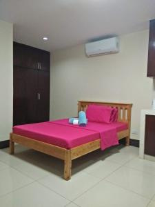 马尼拉卢尔德宾馆的一间卧室配有一张带粉色床单的木床