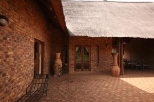 贝拉贝拉Makhato Bush Lodge 109的砖砌建筑,设有草屋顶和庭院