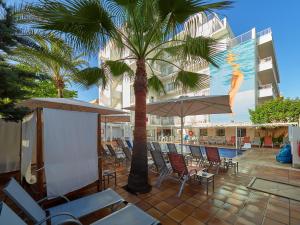 帕尔马海滩BQ Carmen Playa- Adults Only的一个带椅子和遮阳伞的庭院和棕榈树