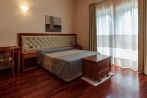 圣安蒂奥科Hotel Del Corso的一间卧室配有一张床、一张桌子和一个窗户。