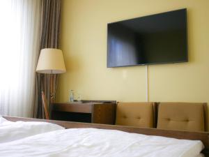 科布伦茨Hotel Oronto的酒店客房设有一张床和墙上的电视