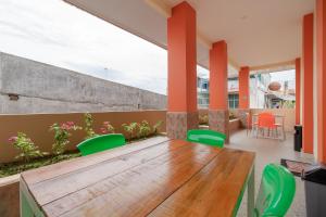 班达亚齐RedDoorz Syariah @ Panglima Polem Aceh的庭院配有木桌和绿色椅子