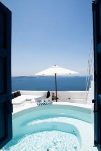 伊亚Oia's Secret的一个带遮阳伞和海洋的按摩浴缸