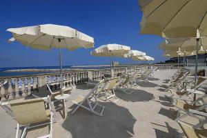 圣温琴佐彼雅尼别墅酒店的海滩上的一排椅子和遮阳伞