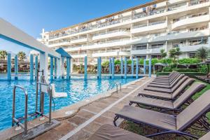 阿尔库迪亚港奥纳花园湖泊公寓式酒店的一座大楼前的游泳池,配有躺椅