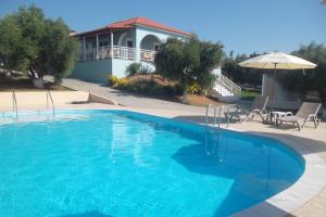 基利尼Kastro Beach Hotel的一个带遮阳伞和房子的大型蓝色游泳池