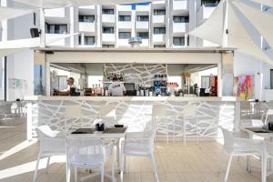 伊维萨镇Apartamentos Vibra Jabeque Soul-3SUP的一间设有白色桌椅的餐厅,以及一座建筑