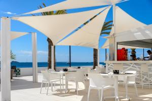 伊维萨镇Apartamentos Vibra Jabeque Soul-3SUP的一间设有白色桌椅的海洋餐厅