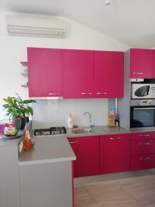 古维达里Apartments Hana的厨房配有明亮的粉色橱柜和水槽